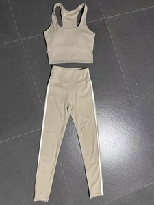 Flat lay of beige two-piece yoga set with racerback bra and striped high-waisted leggings