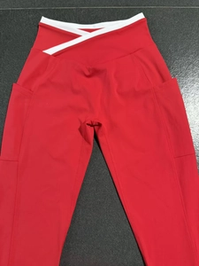 Détail du legging de yoga rouge avec taille croisée blanche et poches latérales