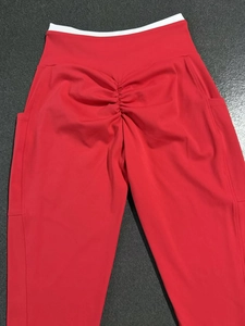 Détail du legging de yoga rouge avec taille haute contrastée blanche et effet scrunch fessier