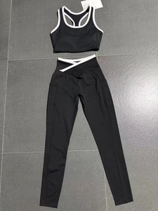 Detailansicht des schwarzen Yoga-Sets mit weißen Kontrastpaspeln an BH und Leggings