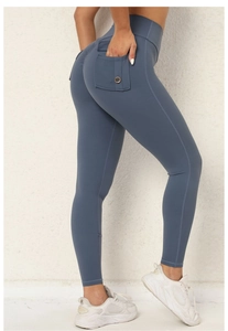 Detail der High-Waist-Yogahose mit seitlicher Pattentasche und braunem Knopf in Schieferblau