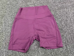 Flat lay of purple high-waisted yoga shorts with reinforced stitching on gray textured mat