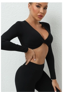 Détail du haut de yoga noir à manches longues avec décolleté en V et nœud frontal