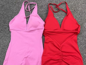 Flat lay of ruched halter neck one-piece fitness jumpsuits in pink and vibrant red colors
