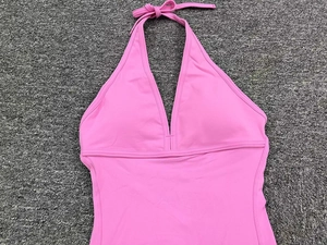 Flat lay detail of a light pink halter-neck one-piece yoga jumpsuit with V-neckline