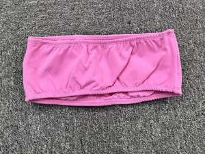 Detailed flat lay of pink strapless yoga bandeau with elasticated edges on textured rug