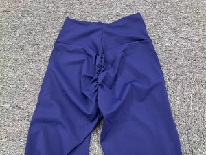 Dettaglio dei pantaloni yoga a campana viola scuro a vita alta con design arricciato push-up