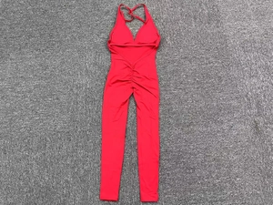 Detail of red backless yoga jumpsuit with ruched peach lift design on gray carpet