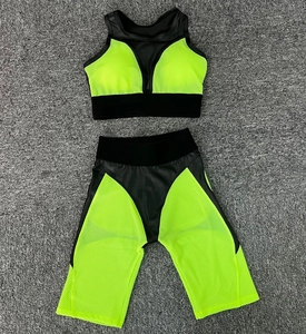 Detailed flat lay of neon green and black yoga set with mesh panels on textured rug