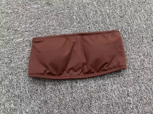 Flat lay of brown strapless yoga bra made of elastic knit fabric on a textured rug