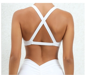 Detail of white sports bra with cross-back straps and high-waisted leggings with V-seam