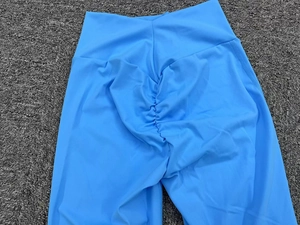 Dettaglio dei pantaloni da yoga azzurri a vita alta a V con design scrunch per sollevare i glutei