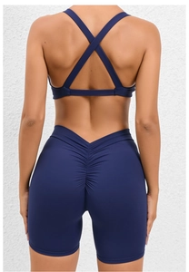 Detail view of navy blue ruched booty shorts and criss-cross back sports bra on model
