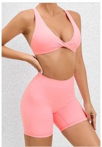 Detail of coral pink sports set featuring front twist knot vest and high waist cycling shorts