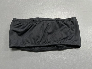 Detail of black pleated strapless sports bra with elastic ribbed texture on grey background