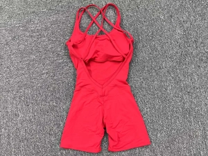 Detail of red backless yoga jumpsuit featuring criss-cross straps and elastic fabric