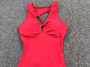 Macro detail of red high-elastic yoga bodysuit featuring chest knot and criss-cross straps
