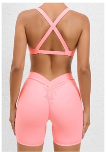 Detail of cross-back sports bra and high-waisted scrunch butt lifting shorts in neon pink