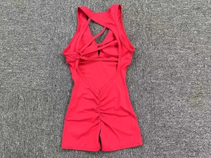 Detail of cross-back straps and ruched seam on a rose red fitness bodysuit