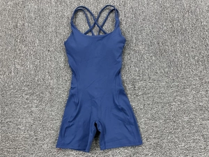 Flat lay of navy blue sports jumpsuit featuring crisscross back straps on grey carpet
