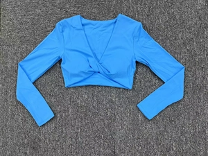 Détail du haut court bleu clair avec décolleté en V profond et nœud torsadé sur l'ourlet