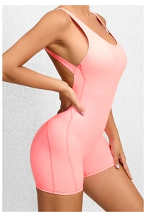 Detail of peach pink open back yoga bodysuit with cross straps and fitted shorts