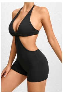 Detail view of black cut-out yoga jumpsuit with halter neck and pleated twist design