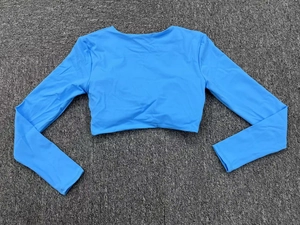 Haut de yoga court à manches longues bleu ciel en tissu élastique sur fond gris texturé