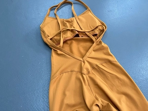 Detail eines gelben Yoga-Jumpsuits mit gekreuzten Rückengurten und V-förmiger Naht