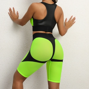 Women's back view of neon green and black patchwork yoga set with mesh cycling shorts