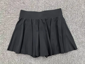 Détail de la jupe de tennis plissée noire avec taille haute sur tissu gris chiné