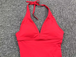 Detailed close-up of red halter neck yoga bodysuit with stretch fabric and V-neck design