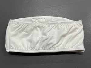 Close-up of white strapless yoga tube top featuring elastic pleated edges on grey leather