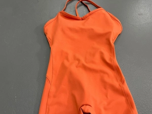 Detail eines hellorangen Yoga-Bodysuits mit V-Ausschnitt und gekreuzten Trägern