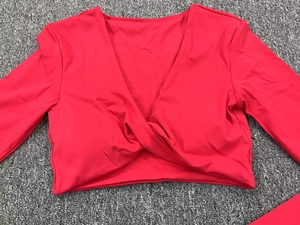 Détail du haut de yoga rouge ajusté avec col en V profond et nœud torsadé à la base
