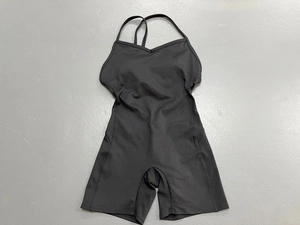 Dettaglio body nero da yoga con spalline sottili e scollo a V su superficie piana