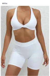 Detail of white cross-back yoga top and high-waisted shorts on a textured wall background