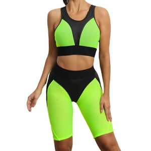 Women's two-piece yoga set with green and black patchwork sports bra and cycling shorts