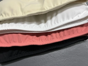 Detail showing the textured knit fabric and reinforced seams of yoga bras in four colors