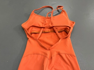 Detailaufnahme des überkreuzten Rückendesigns an einem matten orangefarbenen Yoga-Anzug