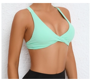 Detail of mint green yoga bra showing the criss-cross knot design and elastic fabric