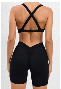 Detail view of black yoga set featuring a cross-back sports bra and ruched lifting shorts