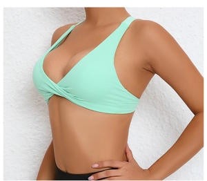 Close-up of mint green yoga bra with cross-pleated design and wide elastic straps