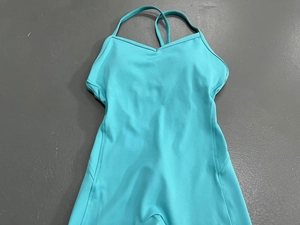 Detailansicht eines mintgrünen Yoga-Jumpsuits mit V-Ausschnitt auf grauem Boden