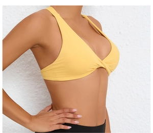 Close-up of yellow sports bra featuring a stylish cross-knot design and elastic fabric