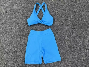 Detailed flat lay of bright blue two-piece yoga set with cross strap bra and high waist shorts