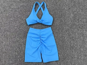 Detail of royal blue yoga set featuring cross back sports bra and ruched gym shorts