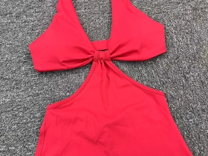 Detail of red hollow yoga bodysuit with halter neck and pleated knot design texture