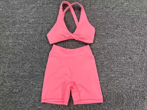 Flat lay of neon pink two-piece yoga set with criss-cross sports bra and high waist shorts