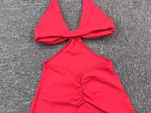 Detailed view of red halter one-piece swimsuit with waist cut-outs and ruched texture